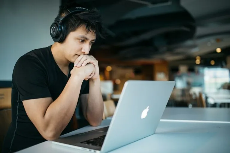 A guy working on his laptop while wearing headphones.