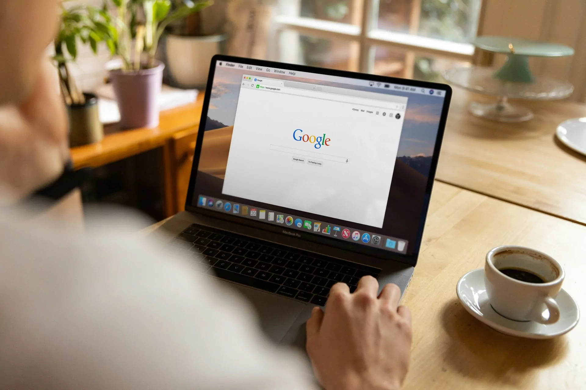 Um homem olhando para a página inicial do Google na tela do seu laptop.