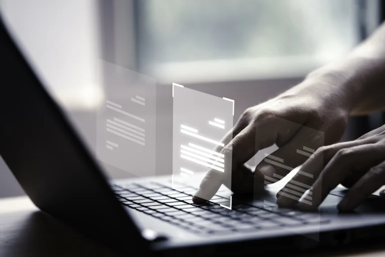 Mãos digitando em um notebook com a ilustração de documentos em cima