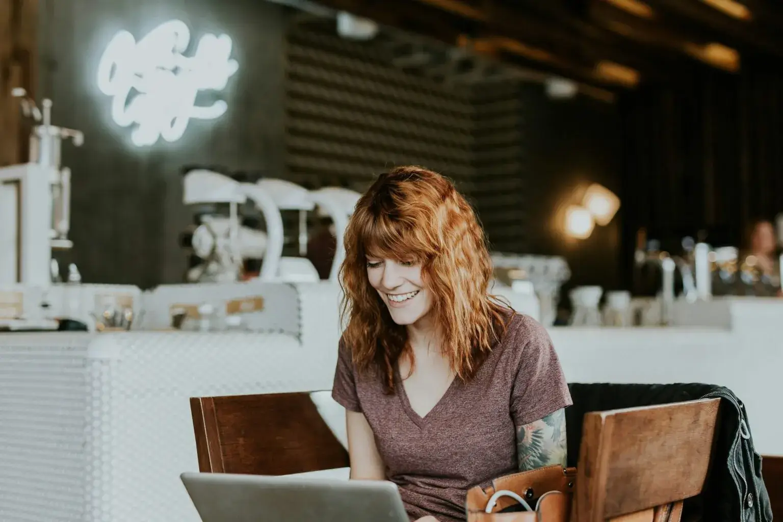 Una mujer autónoma trabajando en una cafetería. Consejos para la gestión del tiempo de los autónomos.