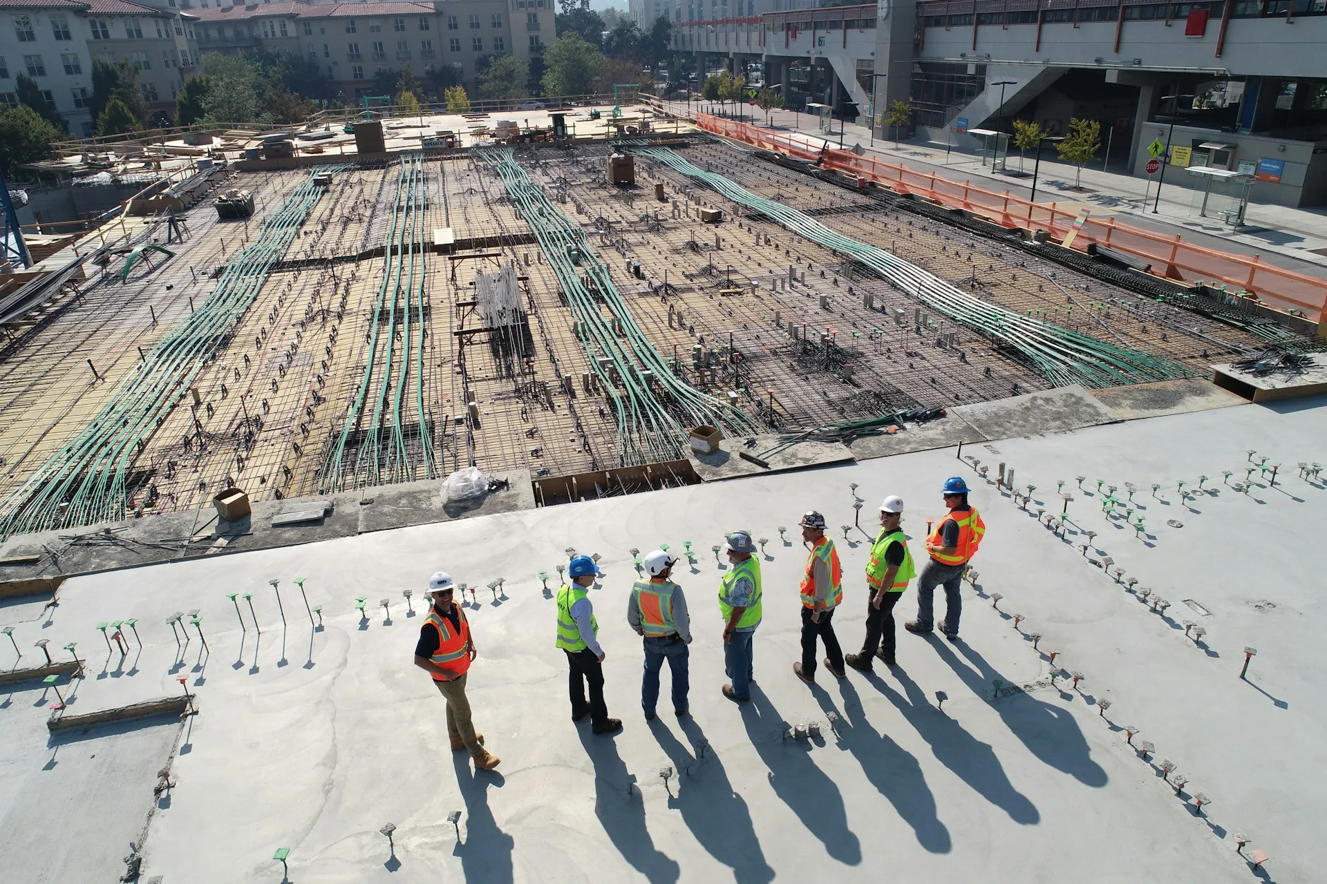Un equipo de construcción de pie uno al lado del otro mientras observan una obra. Seguimiento del tiempo de construcción en múltiples obras.