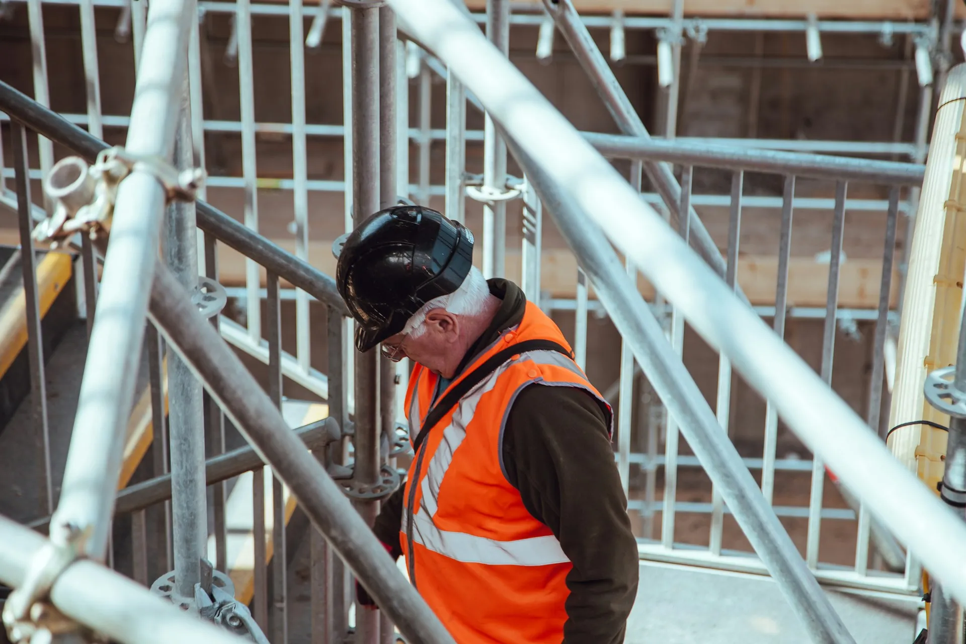 Un operaio edile che indossa un giubbotto arancione di sicurezza in un cantiere edile.