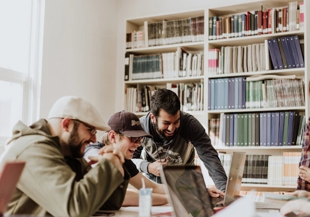 Un grupo de empleados riendo y trabajando con sus ordenadores portátiles en la oficina.