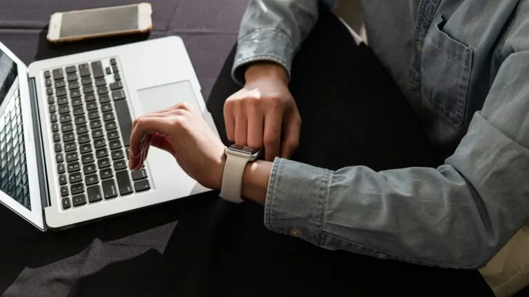 Person checking watch while on laptop
