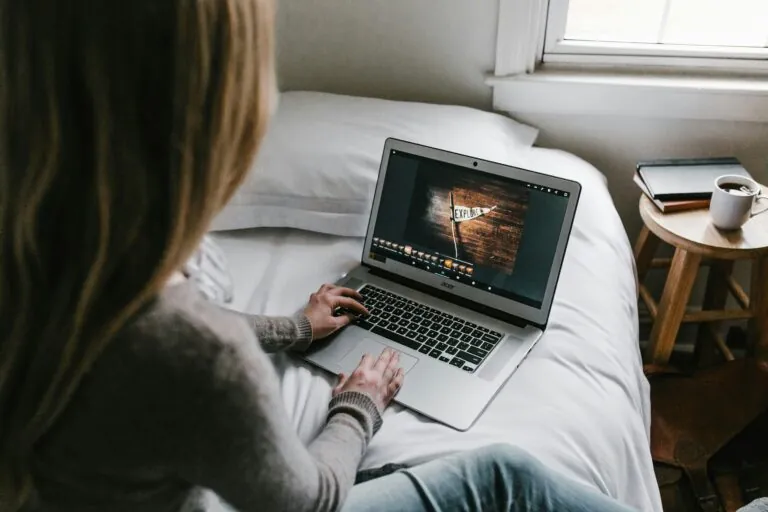 Donna seduta su un letto che utilizza un computer portatile